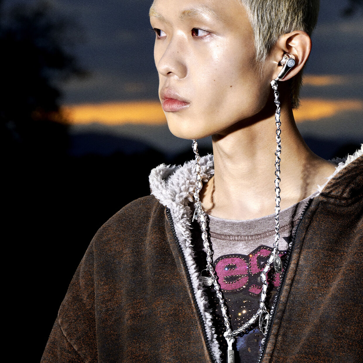 Model wearing the wired headphones in silver with charms, only at Diesel.